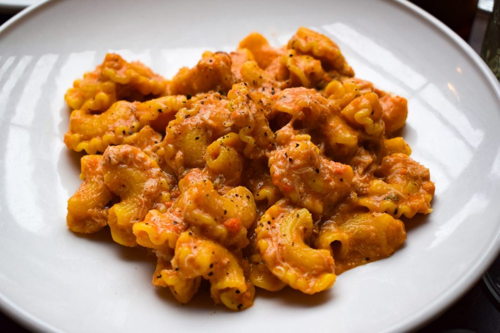 Brown crab pasta in a creamy sauce on a white plate.