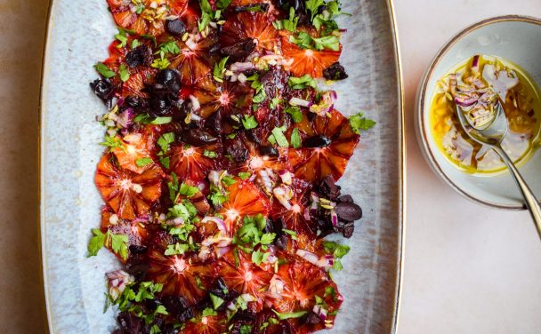 Blood orange and black olive salad with a vibrant bowl of lemon and red onion dressing to one side.