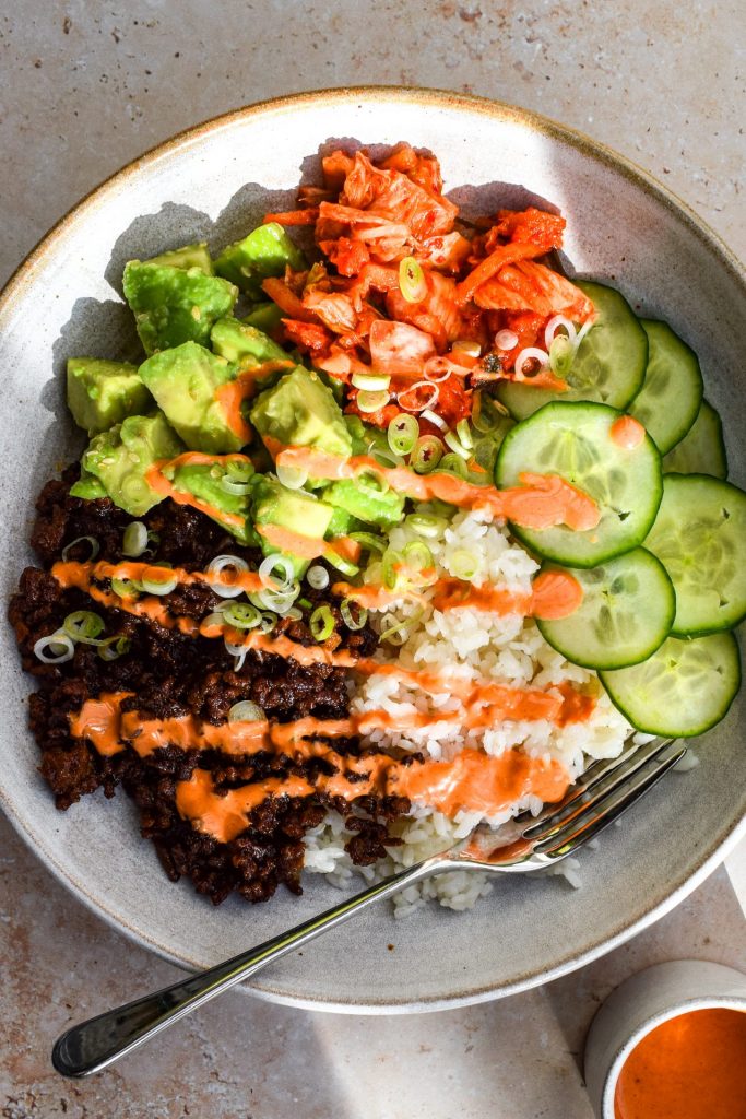 Korean beef mince rice bowl with kimchi, avocado, cucumber and a gochujang drizzle.