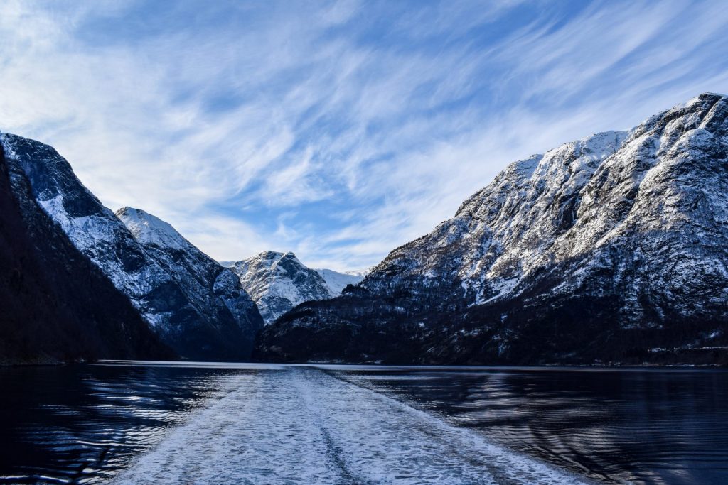 View of Nærøyfjord in the snow from a boat on the water.