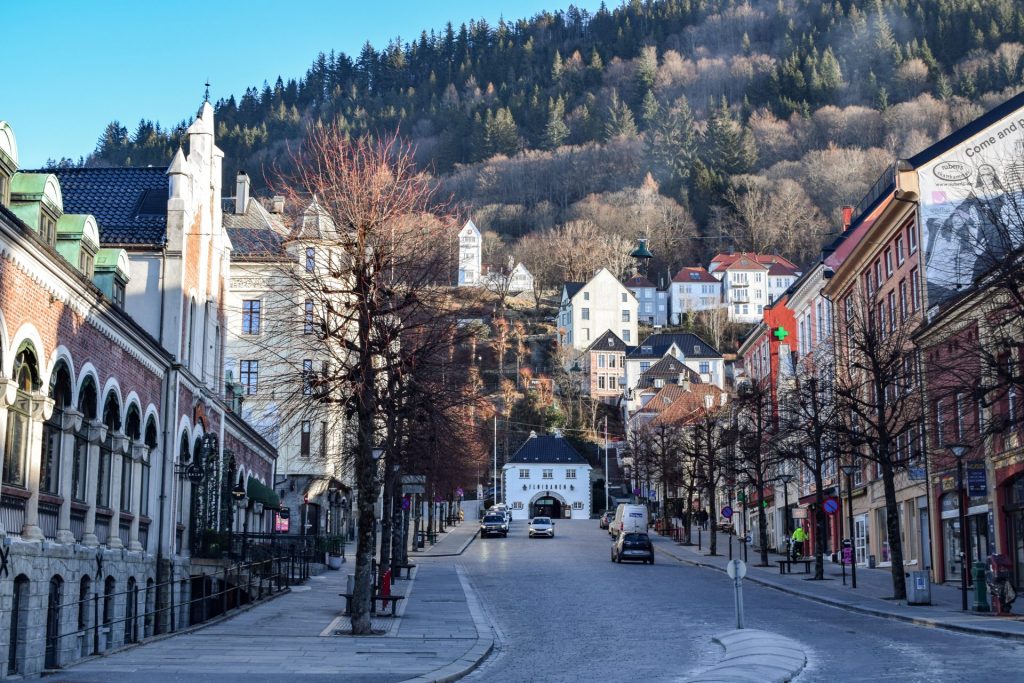 View of a street in Bergen in Winter with tree-covered mountains in the background.