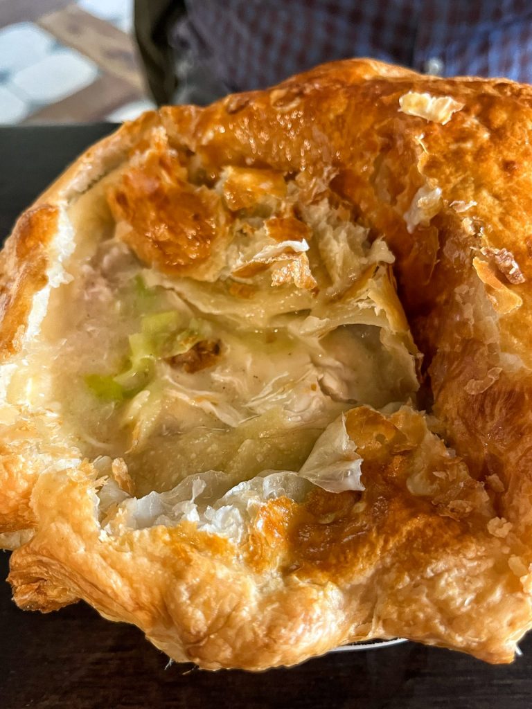 Close up of a chicken and leek pot pie with part of the lid removed to show the filling.
