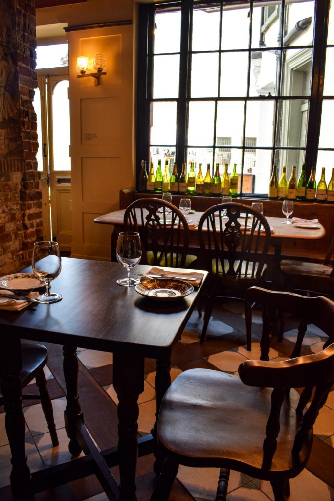 Empty dining room at The Wellington in Margate. There is a row of empty wine bottles lined up in the pub window.