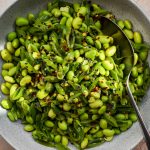Edamame and sliced sugar snap pea salad with dried chilli flakes in a grey bowl.