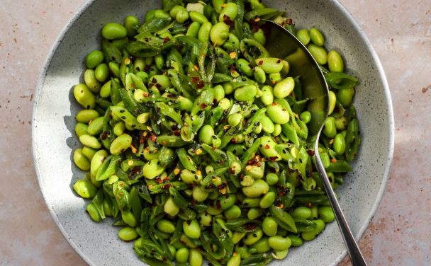 Edamame and sliced sugar snap pea salad with dried chilli flakes in a grey bowl.