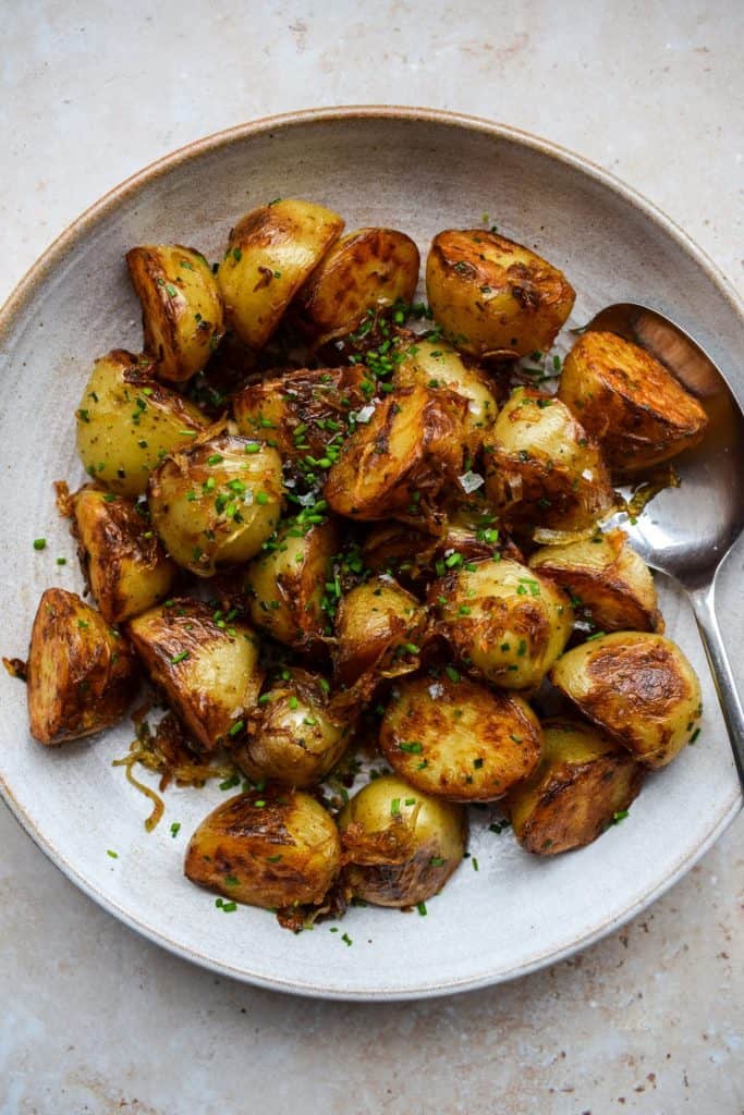Close up of a bowl of Lyonnaise potatoes topped with chopped chives.