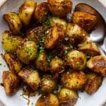 Bowl of golden fried potatoes topped with caramalised onions and fries.