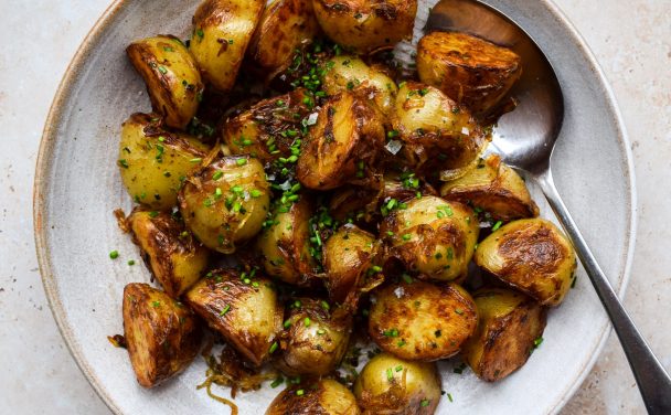 Bowl of golden fried potatoes topped with caramalised onions and fries.