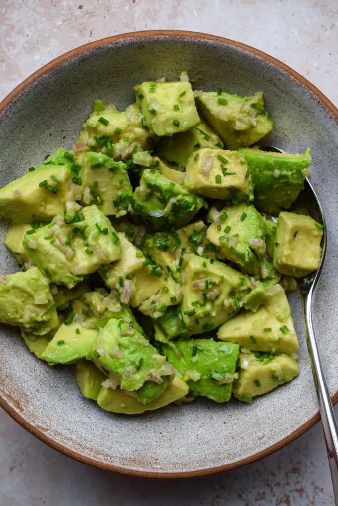 Avocado salad topped with chopped shallots and chives.