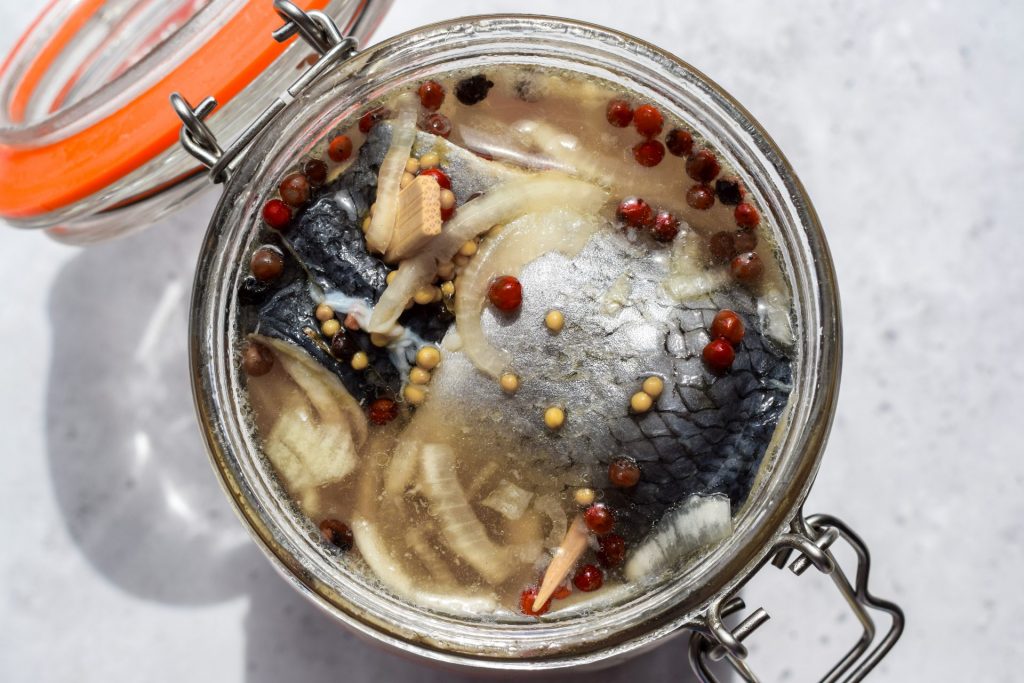 Overhead close up of an open jar of rollmops in direct sunlight.