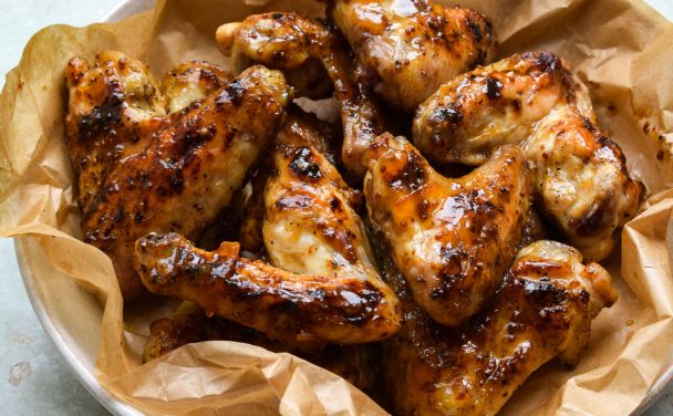 Marmalade and wholegrain mustard glazed chicken wings on a parchment lined plate.