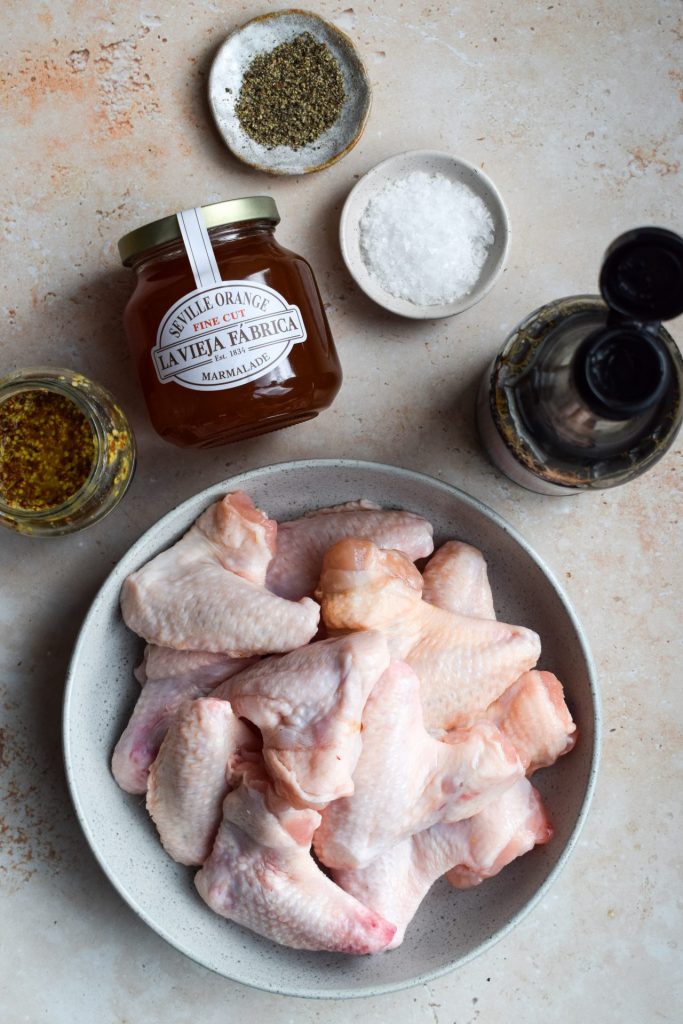 Ingredients to make marmalade chicken wings on a stone background.