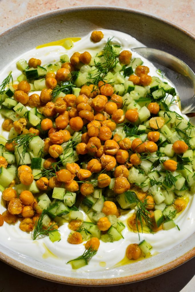 Close up of a bowl of crispy chickpea and cucumber salad-topped yogurt.