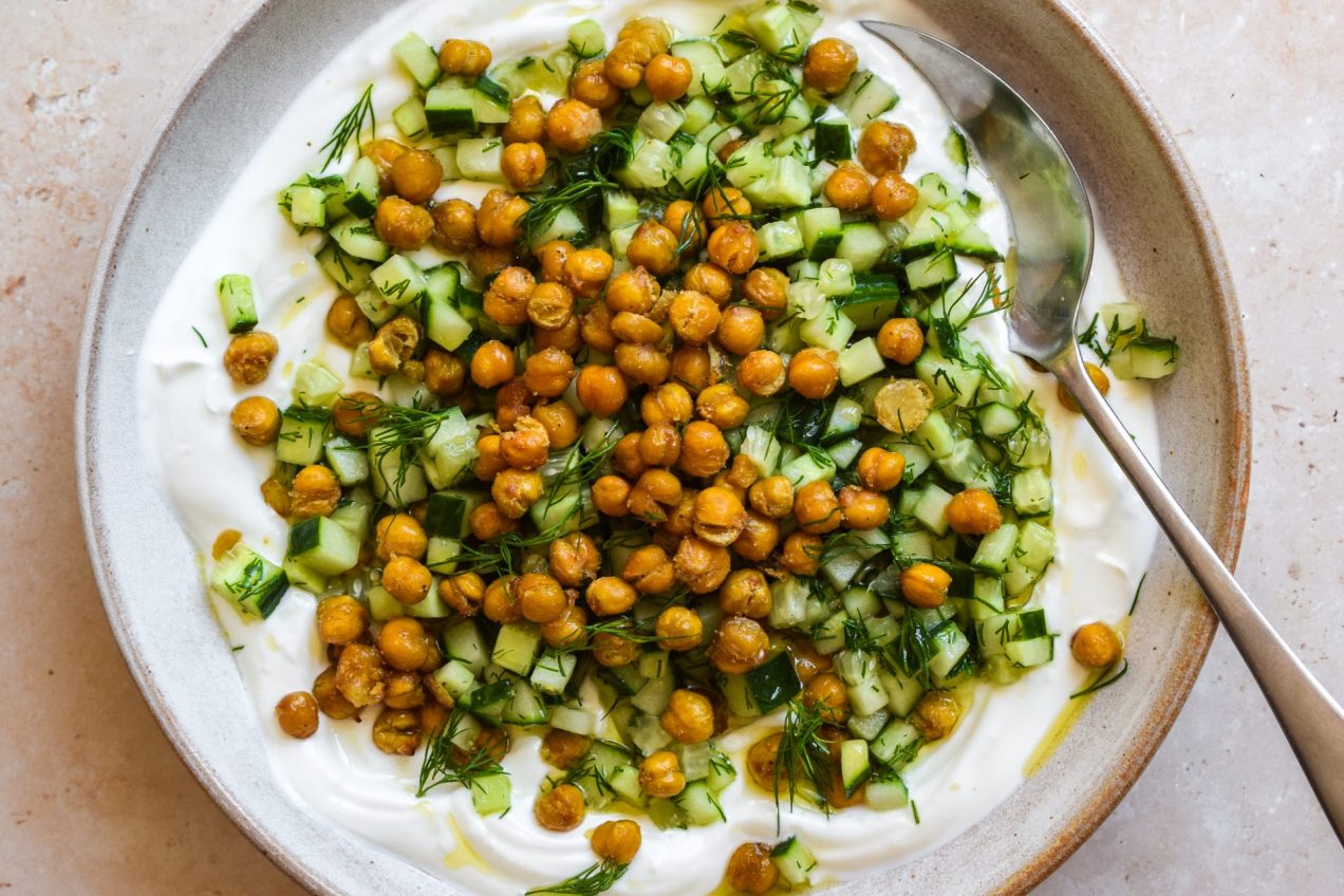 Bowl of crispy chickpeas and chopped cucumber on top of thick yogurt.