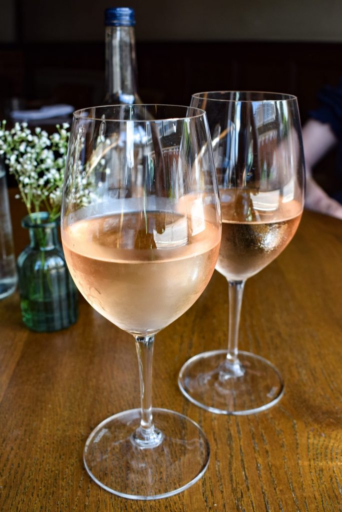 Two glasses of chilled rose wine on a pub table.