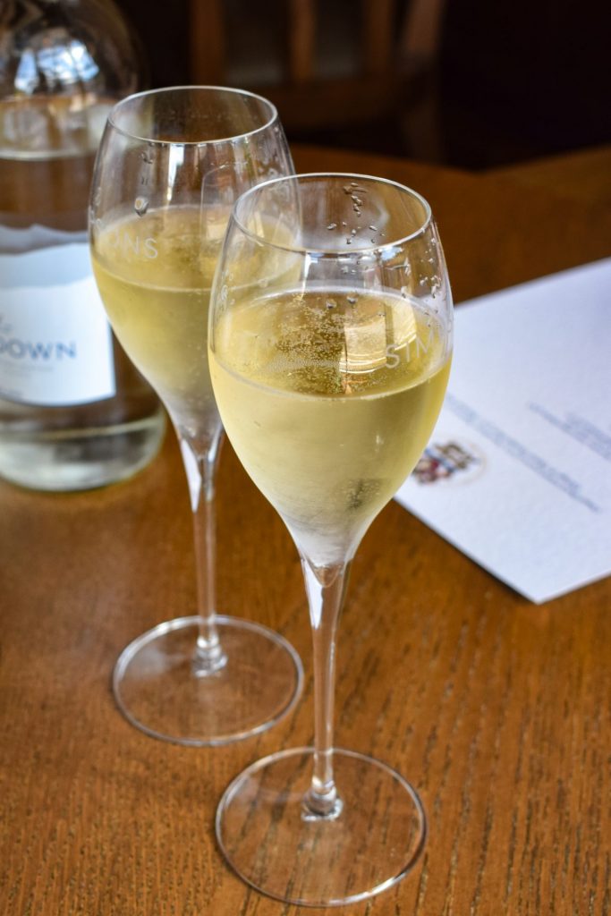 Two glasses of sparkling wine on a pub table.