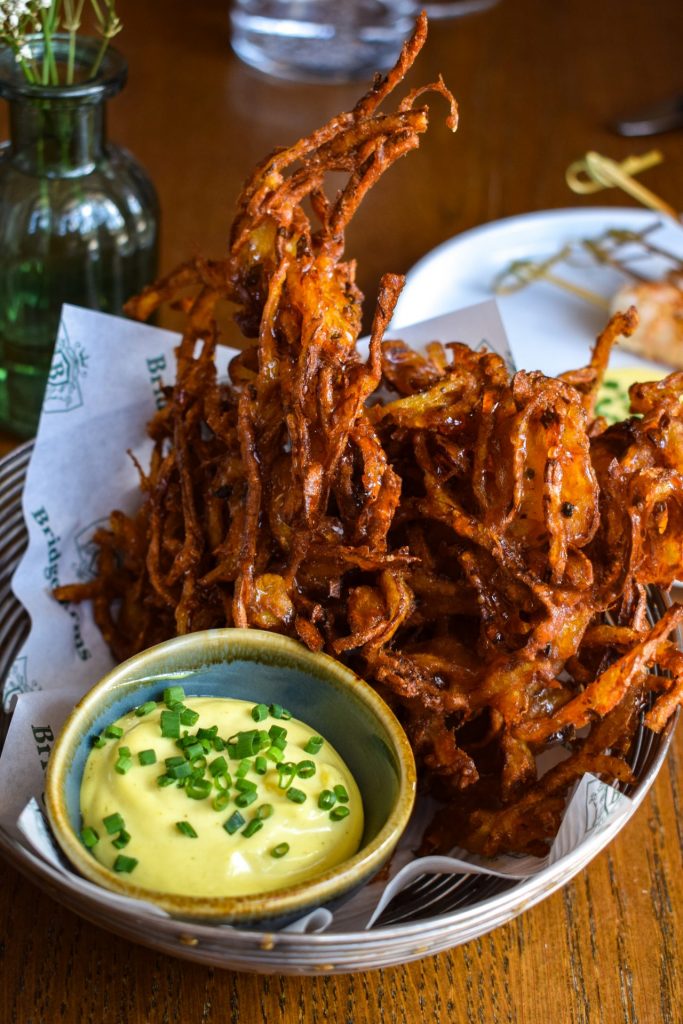 Basked of onion bhajis with a pot of spiced dipping mayo.