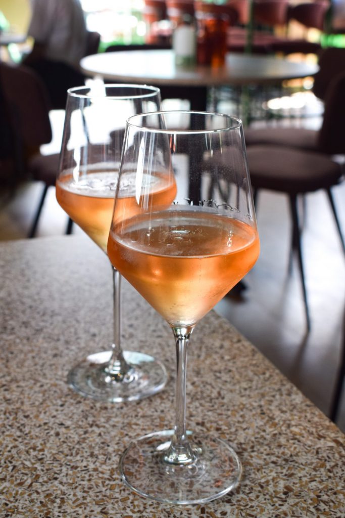 Two wine glasses of sparkling rose wine on a restaurant table.