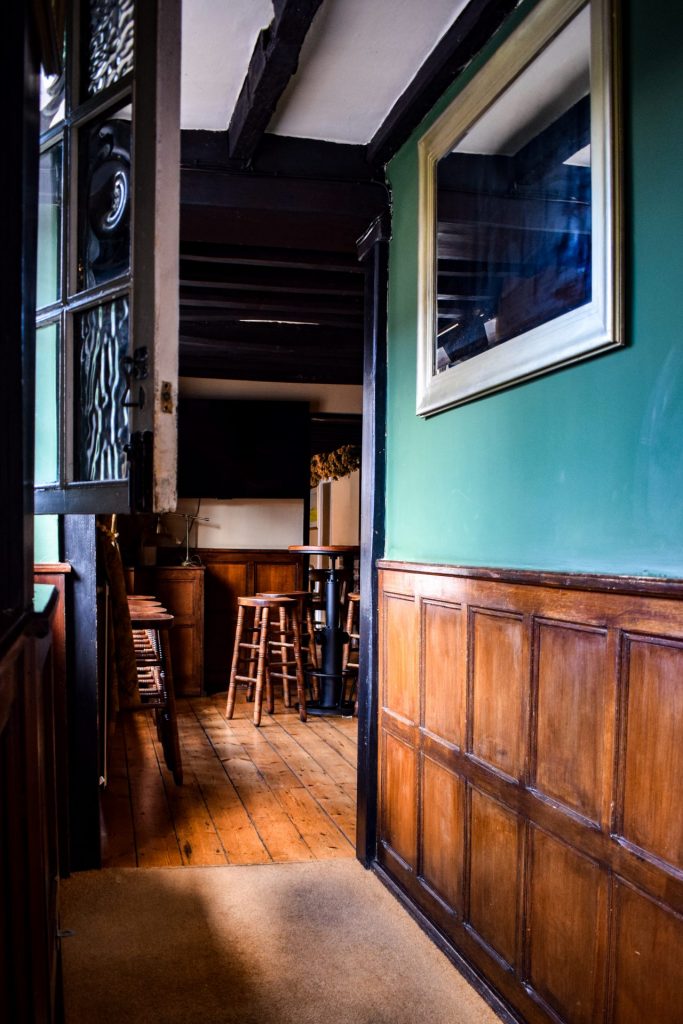 Wood panelled corridor with dark green paint and a mirror on the wall.