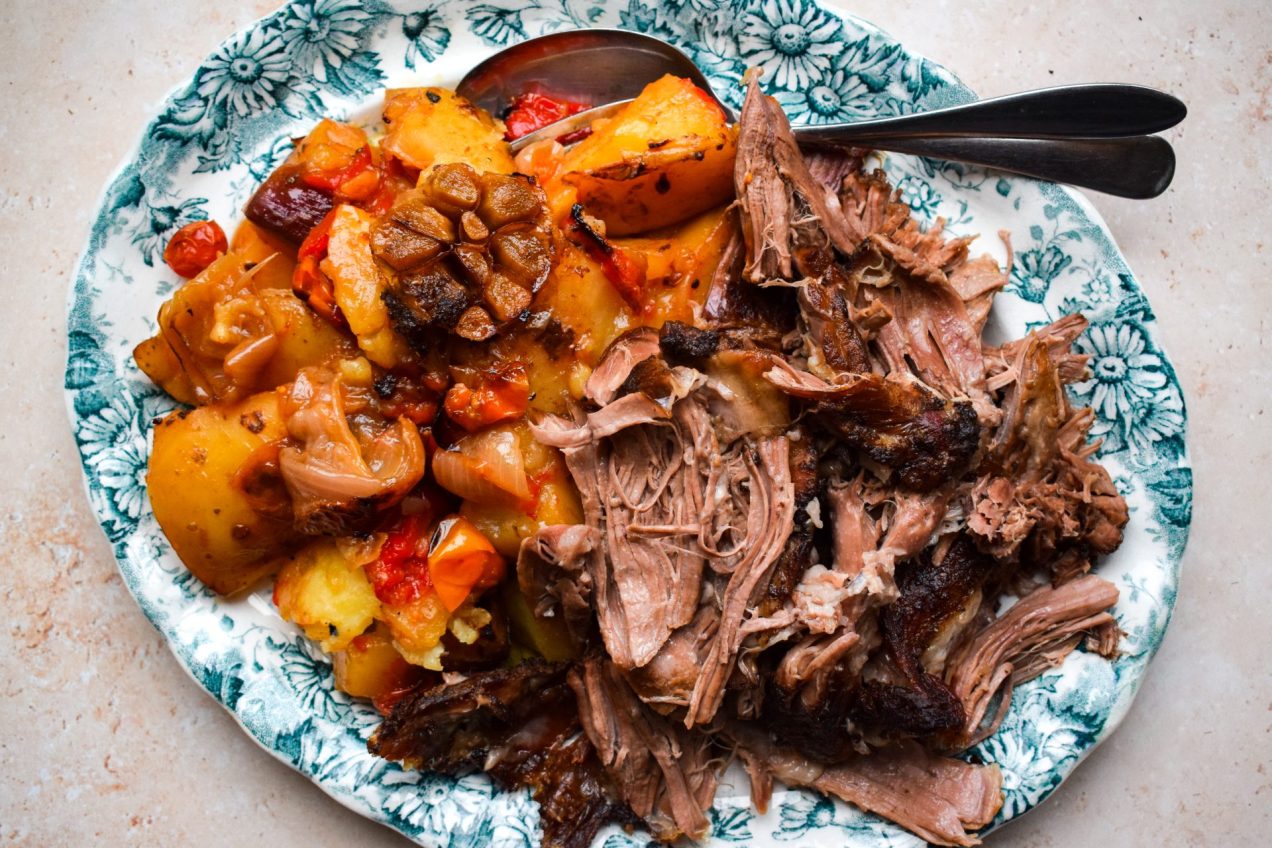 Blue and white platter of shredded lamb shoulder and slow cooked Greek vegetables.