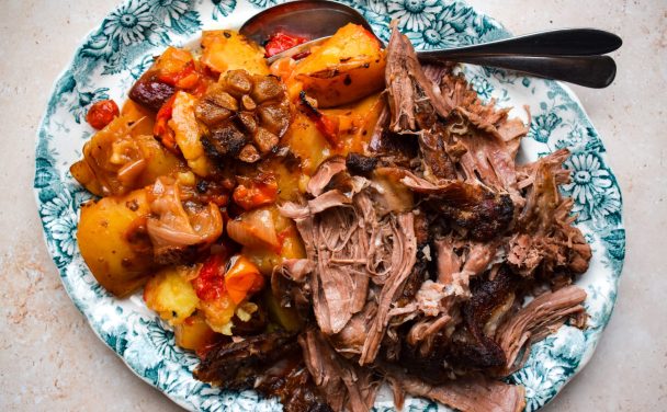 Blue and white platter of shredded lamb shoulder and slow cooked Greek vegetables.