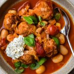 Close up of a bowl of butter beans, turkey meatballs, cherry tomatoes, basil and ricotta.