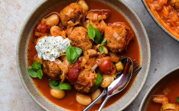 Bowl of turkey meatballs with butter beans, cherry tomatoes, basil leaves and a dollop of ricotta.